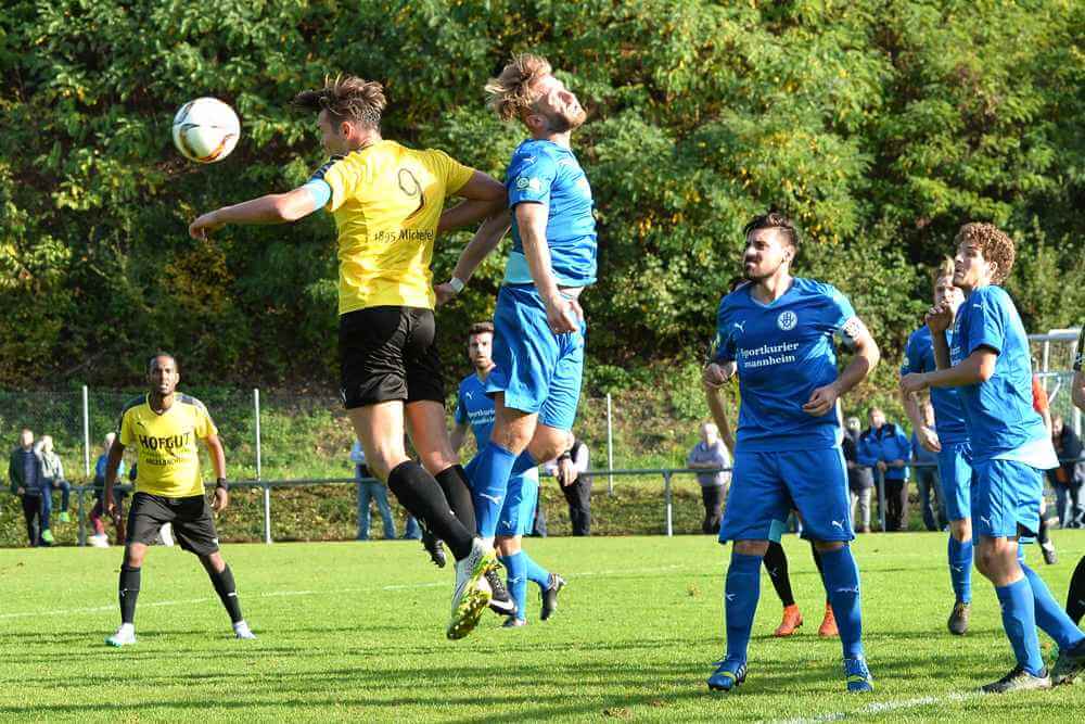 Michelfelds Kapitän und Torjäger Carsten Walther (links) und Heddesheims Daniel Gulde beim Kopfbalduell. Rechts - Giovanni Marino, Richard Wegmann