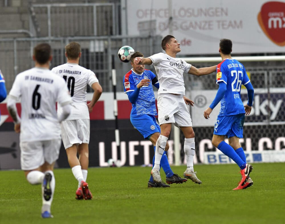 Sandhausens Behrens (weiß) beim Kopfball im Spiel gegen Holstein Kiel. AS Sportfoto