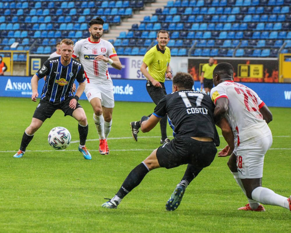 Marcel Costly (SV Waldhof Mannheim, #17) wird von Braydon Manu (Hallescher FC, Nr 28) unter Druck gesetzt, dieser spielt auf Dominik Martinovic (SV Waldhof Mannheim, #11). Bild: Alfio Marino